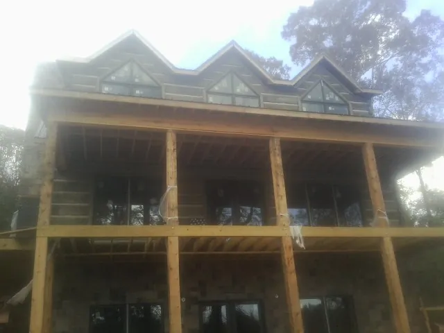 Dormers and porch framing on a large log home under construction — Roof Coating work by our crew in Loysburg