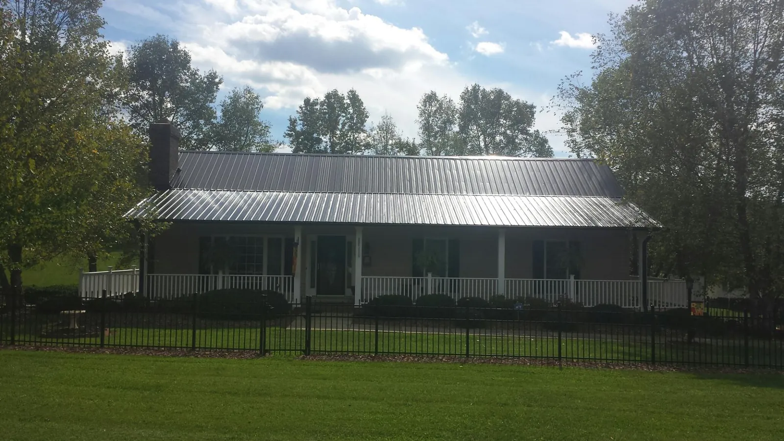 Gray metal roof on a brick ranch with a full width front porch — Gutter Guard Installation work by our crew in Loysburg