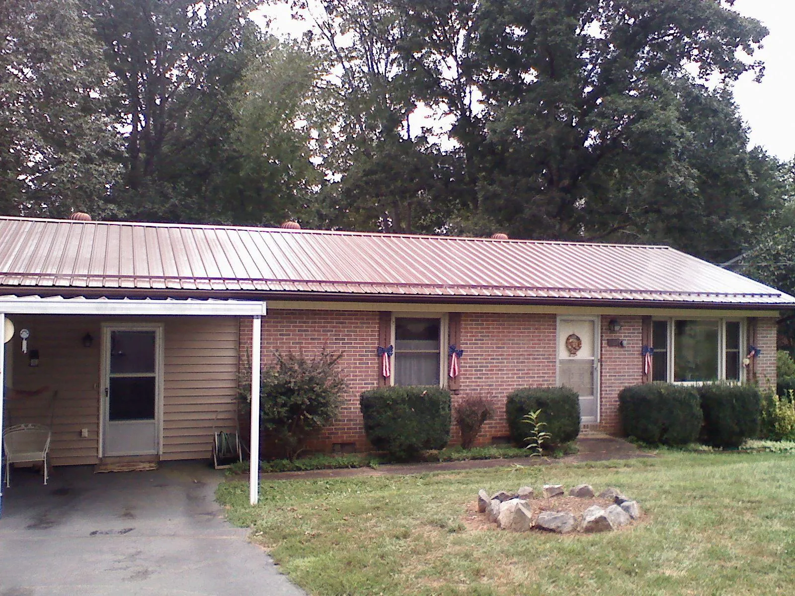 Bronze metal roof and carport on a brick ranch home — Roof Repair work by our crew in Loysburg
