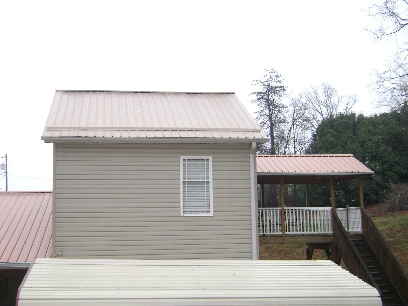 Tan metal roofs on a two story addition and attached porch, from a Roof Replacement job in Loysburg