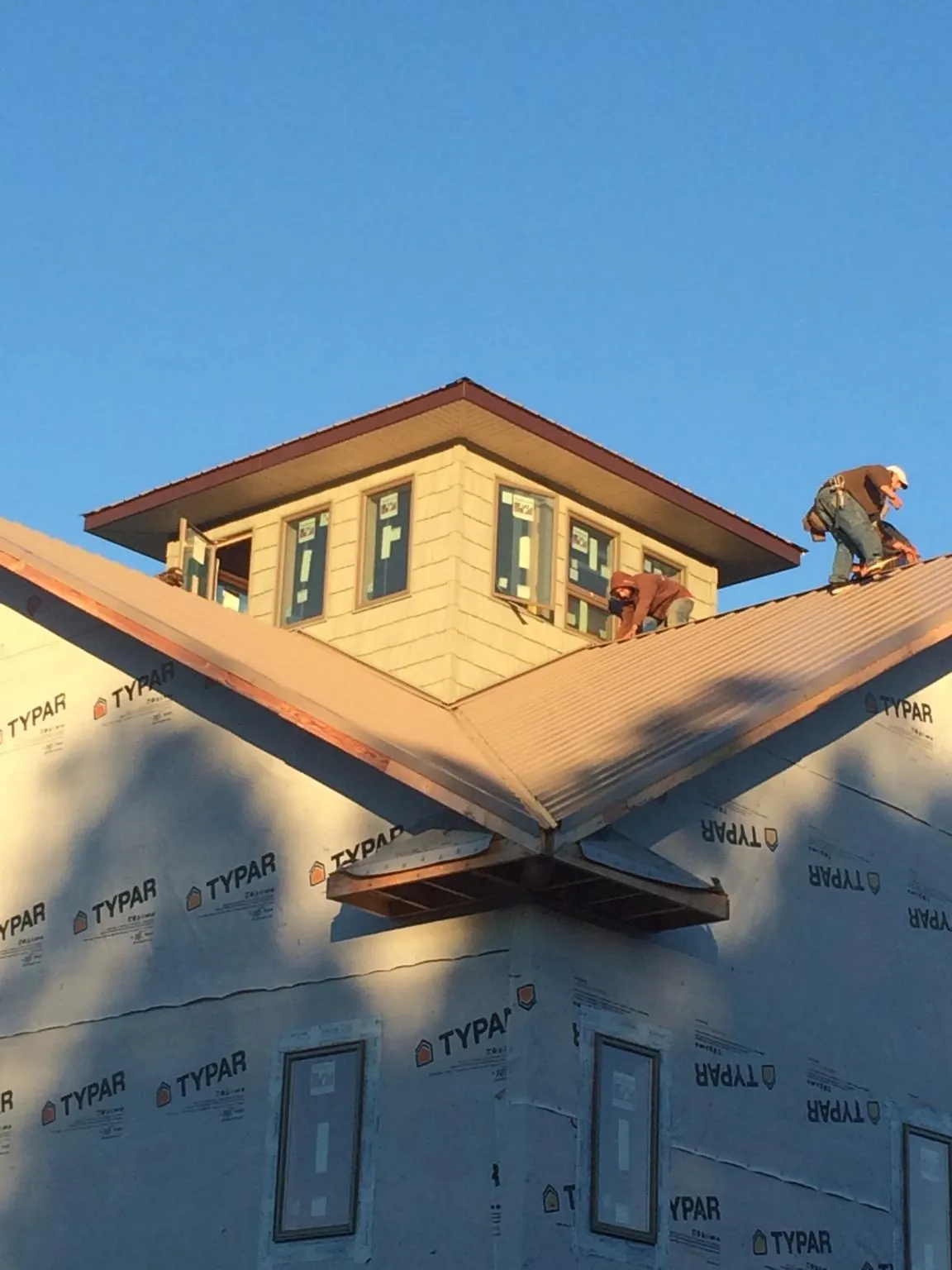Roofers working around a rooftop cupola on a new metal roof at sunset — Roof Waterproofing in Loysburg by Roofing Brothers